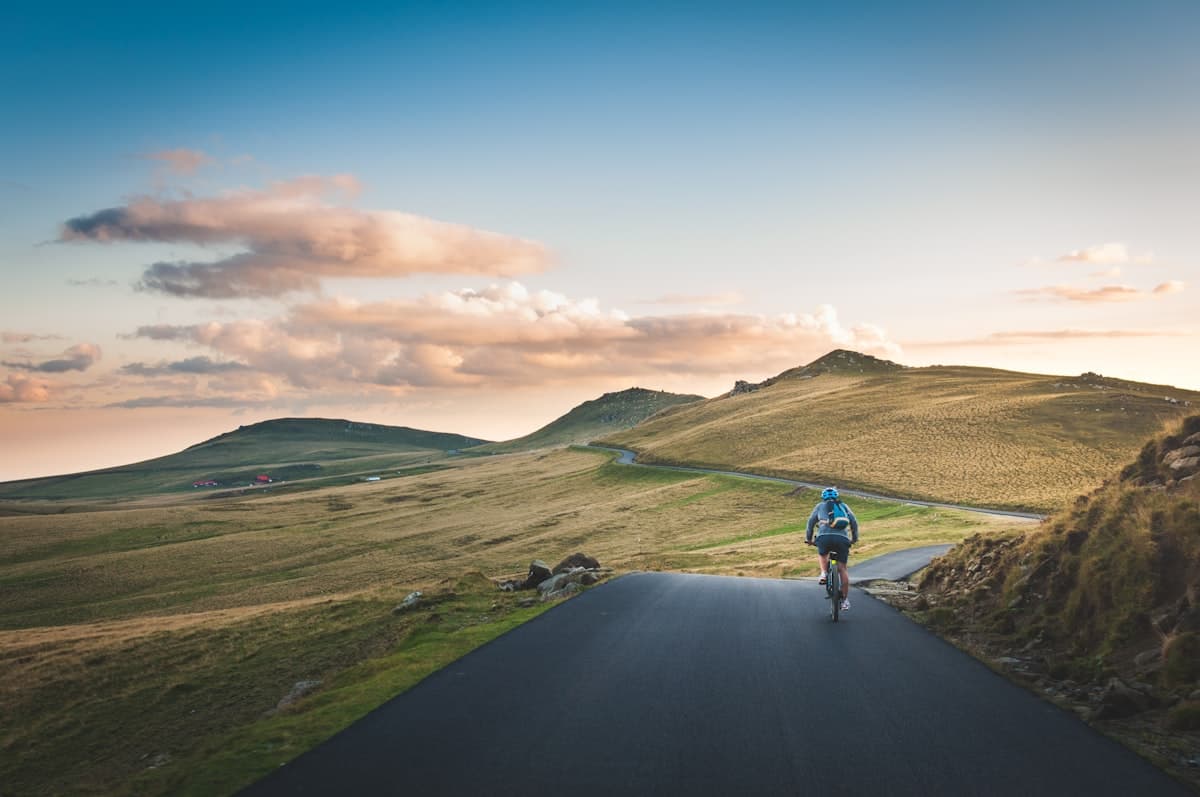A cyclist on a winding road through rolling hills